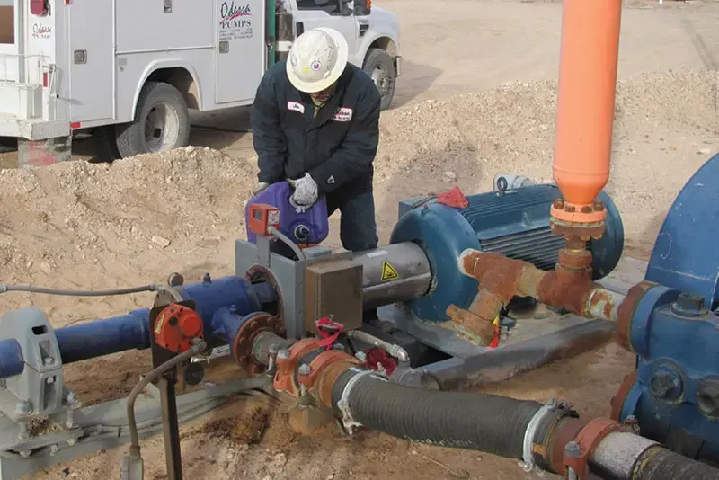 Photo of an Odessa Pumps technician providing pump preventative maintenance in the field to extend the life of the pump